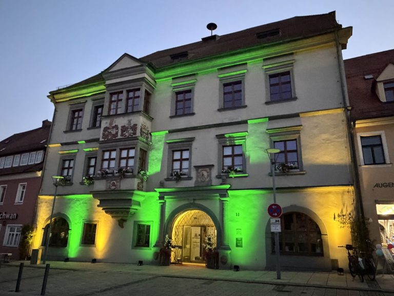 Fassadenbeleuchtung in Grün und Bernstein an einem historischen Gebäude in der Abenddämmerung
